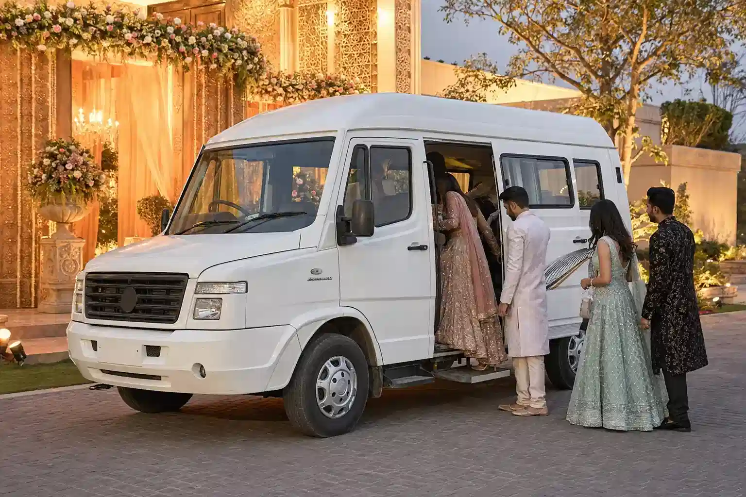 Wedding guests boarding a white Tempo Traveller at a venue in Delhi